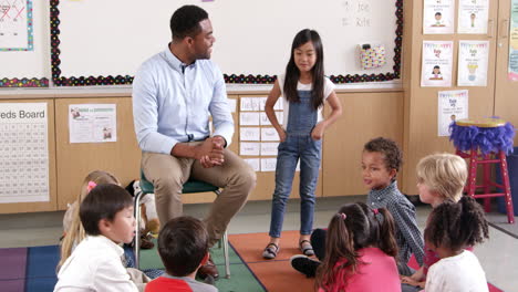 asian schoolgirl standing with teacher in front of class