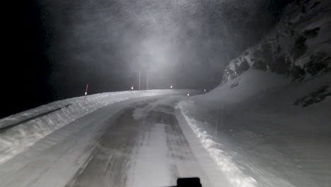driving through a blizzard at night on a snow covered road