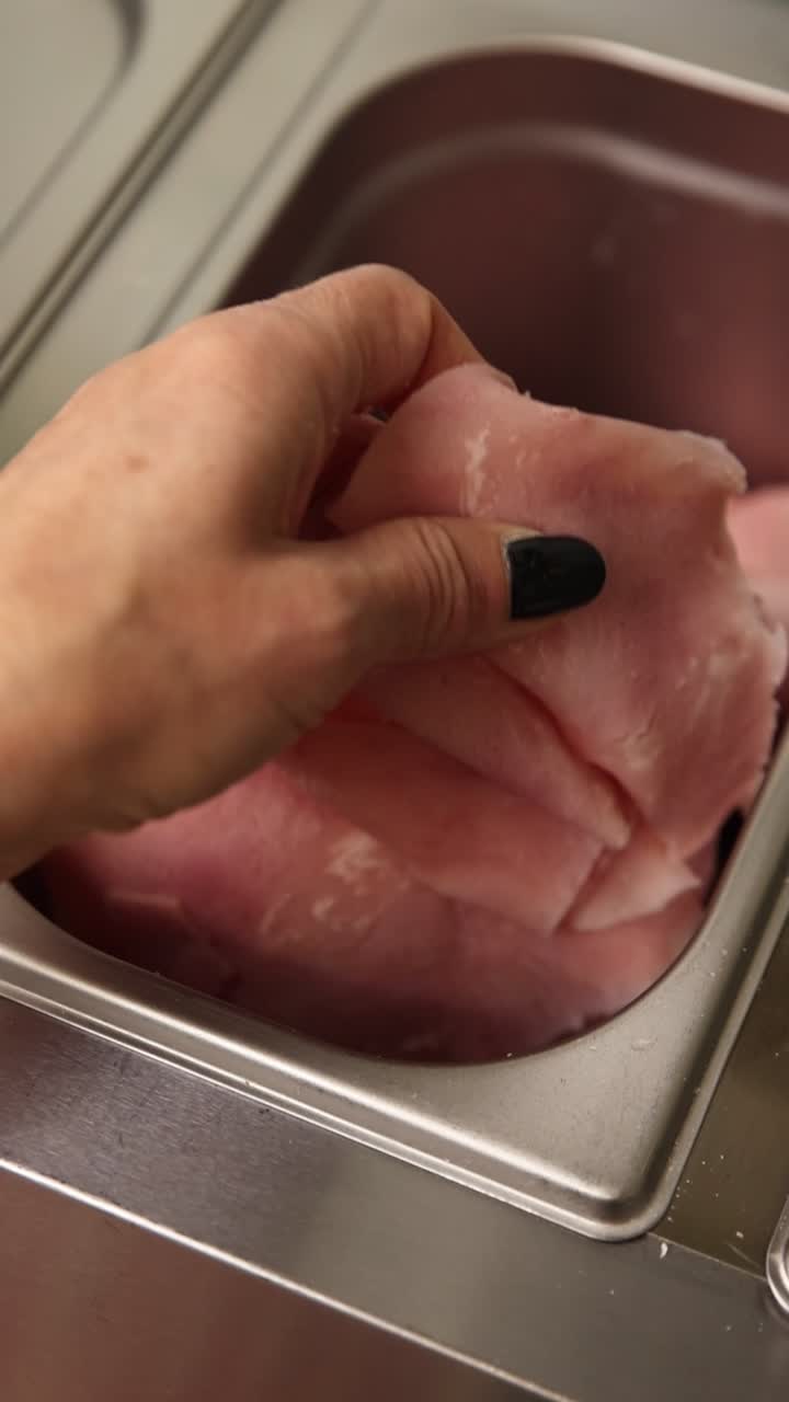 Hand Taking a Slice of Fresh Sliced Ham from a Metal Container
