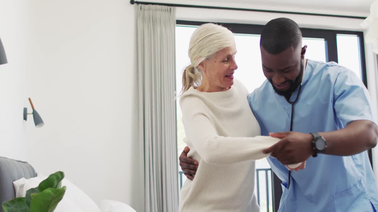 Video of happy african american male doctor taking care of caucasian senior woman