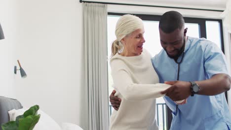 video of happy african american male doctor taking care of caucasian senior woman