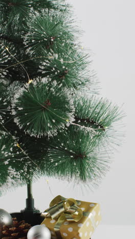 disparo de primer plano vertical de un pequeño árbol de navidad en un soporte de madera sobre un fondo blanco