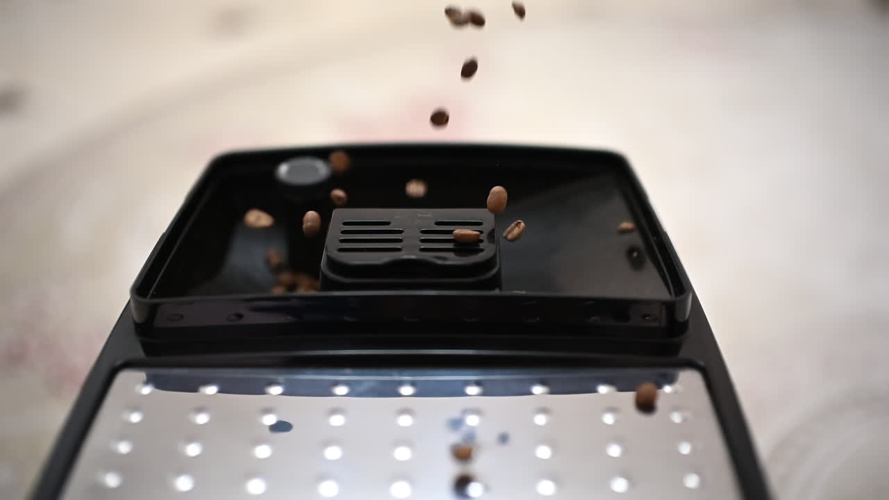 Ripresa al rallentatore di chicchi di caffè che cadono nel contenitore di un macinacaffè