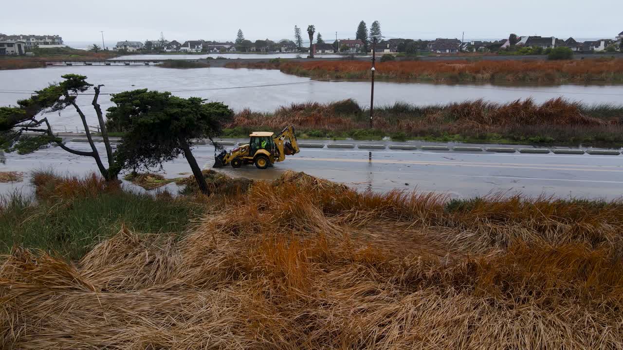 tractor que mueve agua a través de una calle inundada, día lluvioso