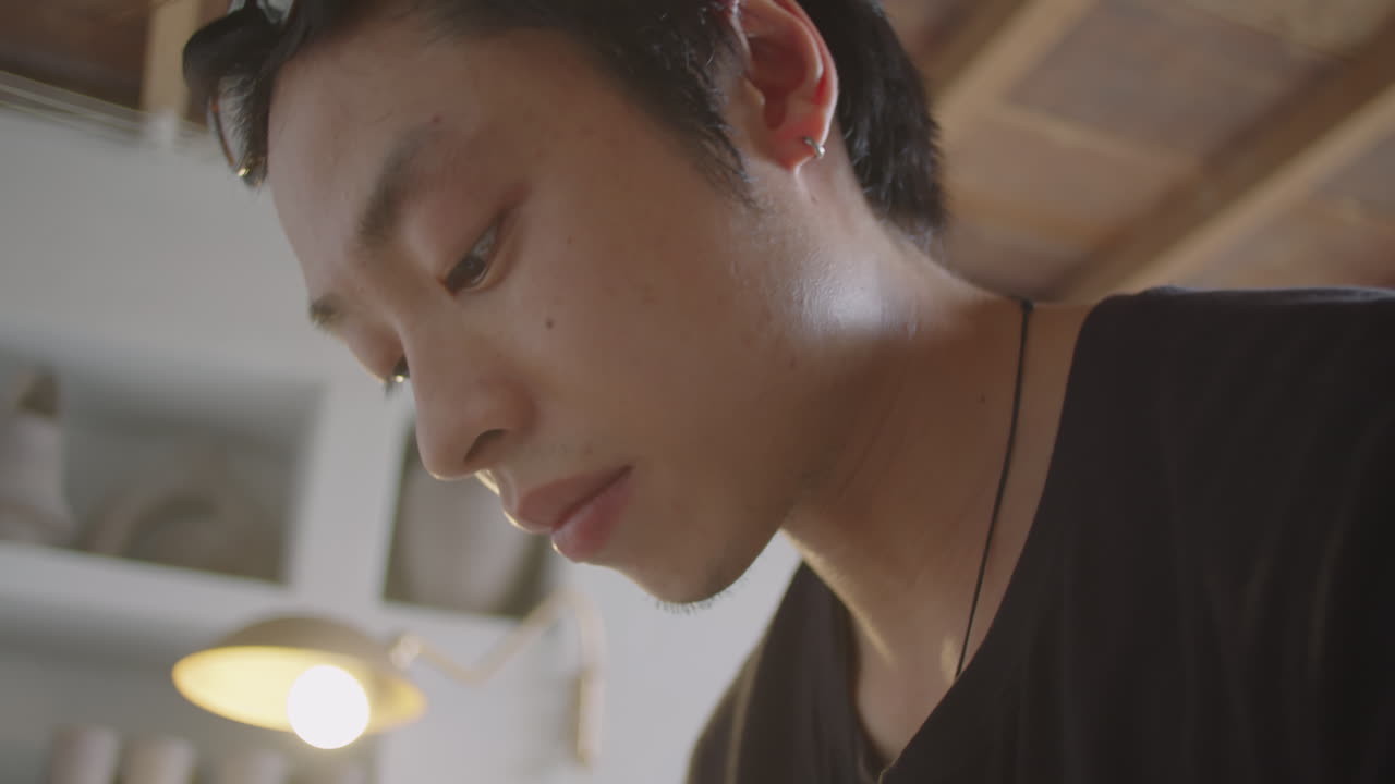 Asian Man Rolling Clay Coil in Ceramics Workshop