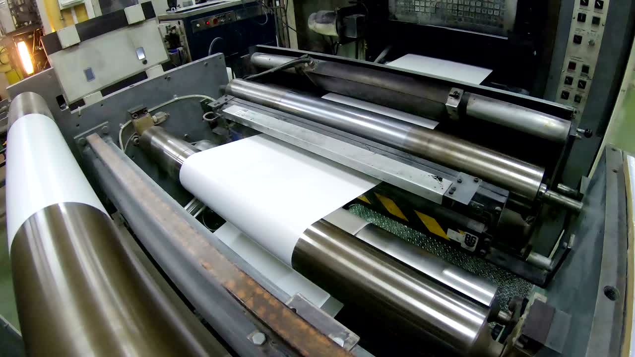 크레인  인쇄 된 오프 롤 종이 인쇄소에서 신문 브로셔의 일부로 롤러로 빠르게 움직입니다.