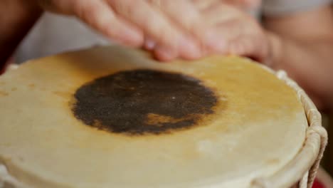 close up of hands of a man playing a drum.