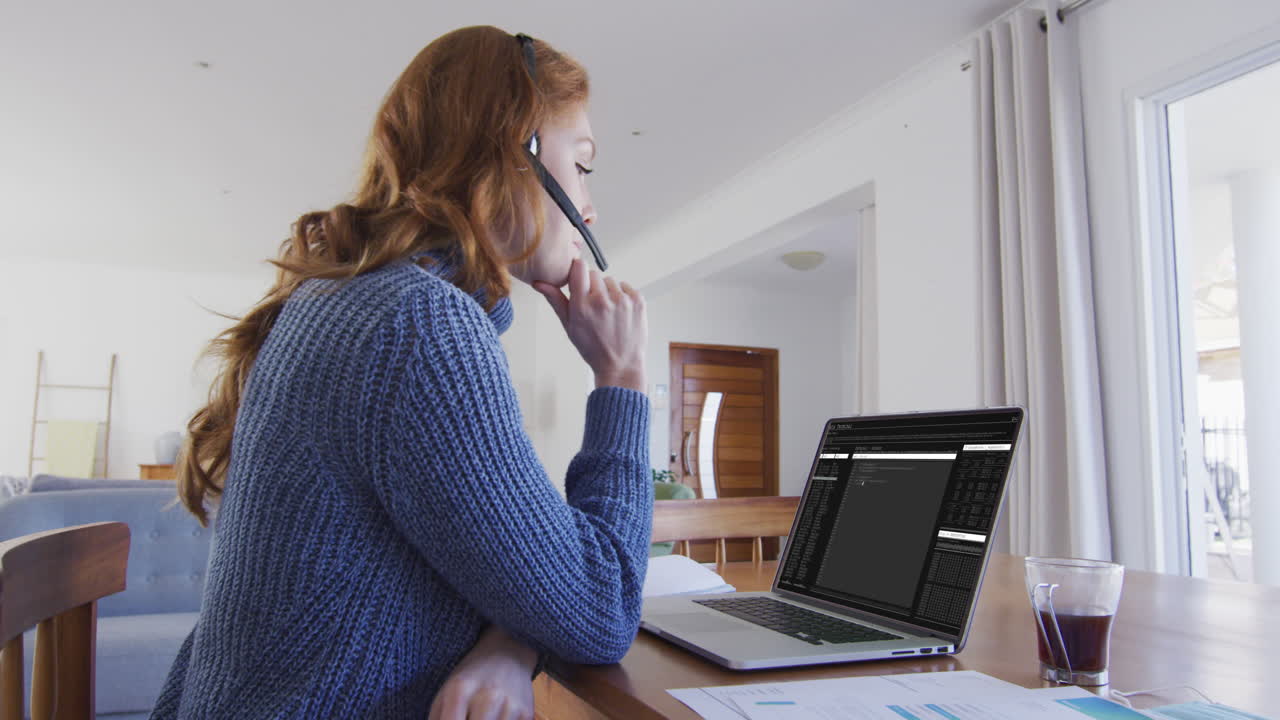 Caucasian woman sitting at desk watching coding data processing on laptop screen