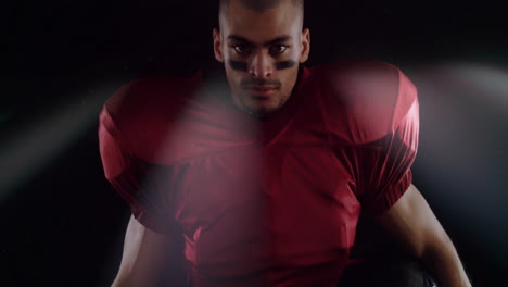 preparing for game, football player in red jersey showing intense focus