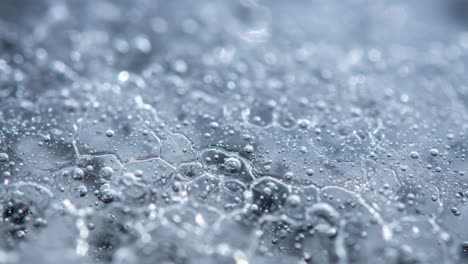 an abstract close-up exploration of bubbles and water droplets on a reflective surface, capturing the intricate patterns and textures created by light reflections