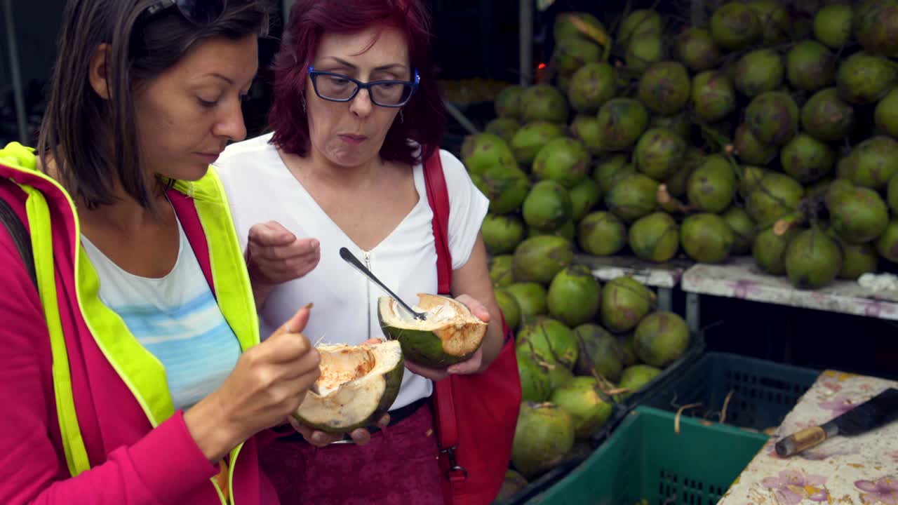 las mujeres comen coco verde joven en la calle