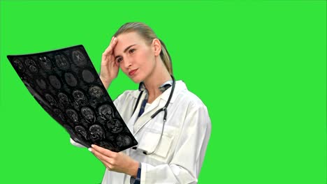médico mujer mirando seriamente los resultados de rayos x del cerebro humano en una pantalla verde, llave de croma