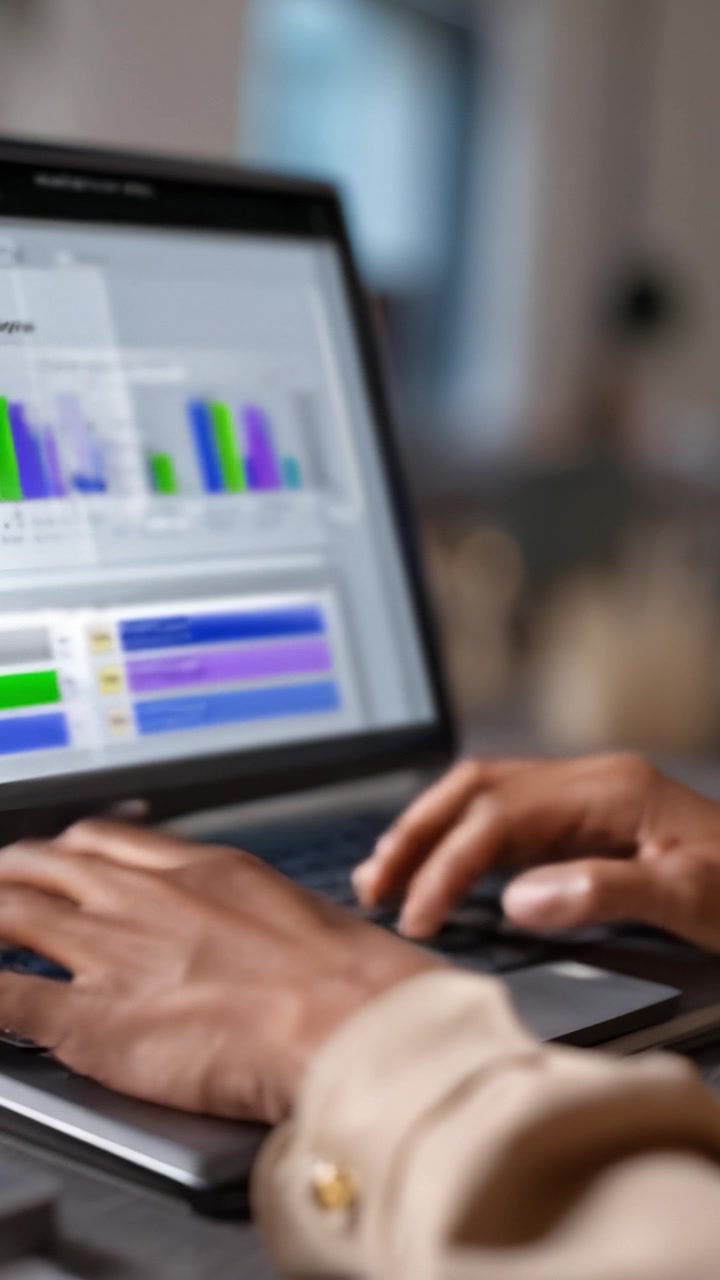 Hands typing on a laptop displaying analytical graphs and data visualizations, focusing on trends and insights in a modern workspace environment.