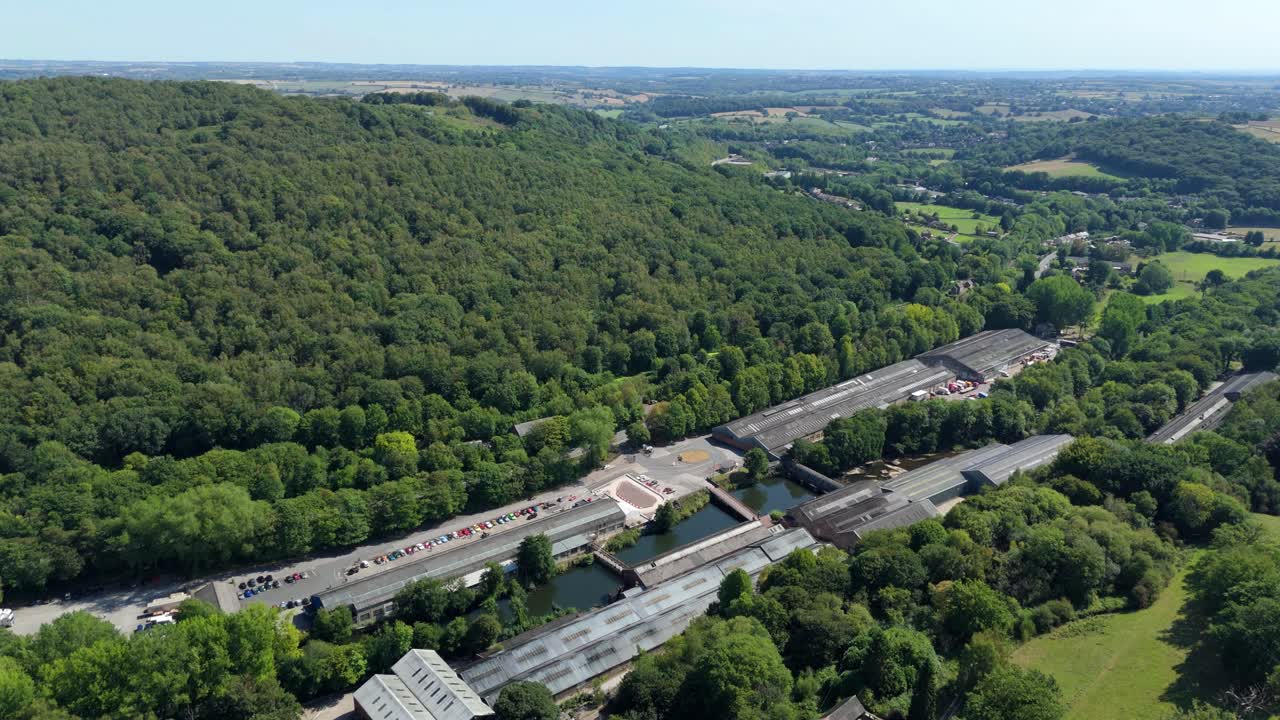 Aerial drone panorama of historic British car factory museum and surrounding green valley in Derbyshire Dales Ambergate England