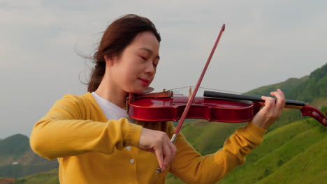 female-musician-plays-the-violin-on-the-top-of-a-mountain-in-Asia