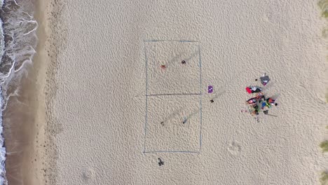 aerial: young people plays volleyball on a sand on a lovely evening