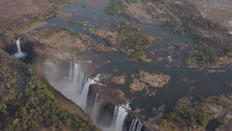 rainbow forms during rotating aerial of unesco famous victoria falls