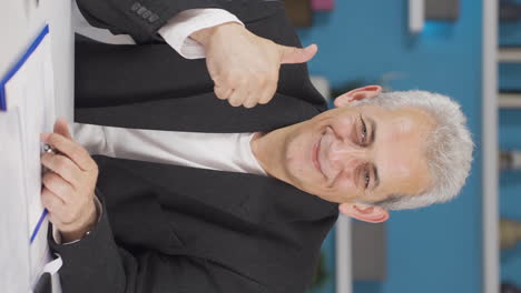 vertical video of home office worker man making positive gesture at camera.