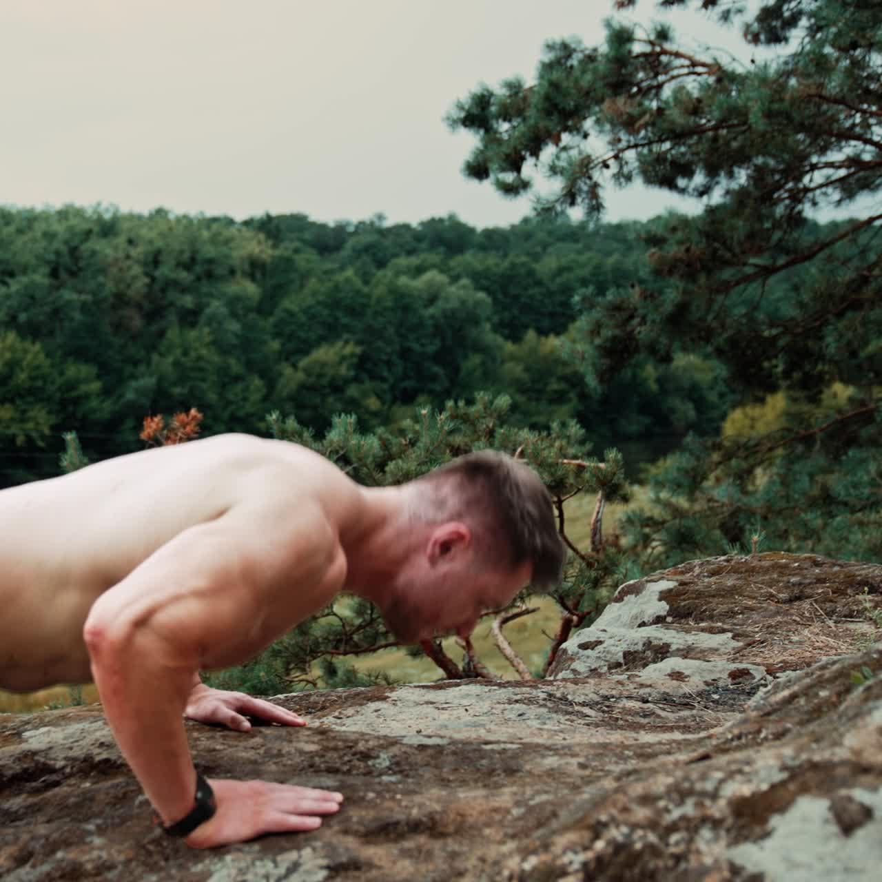 Sportsman doing pushups on the big rock. Exercising, work out and healthy lifestyle in the nature