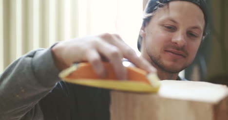 young carpenter sanding wood in workshop 1