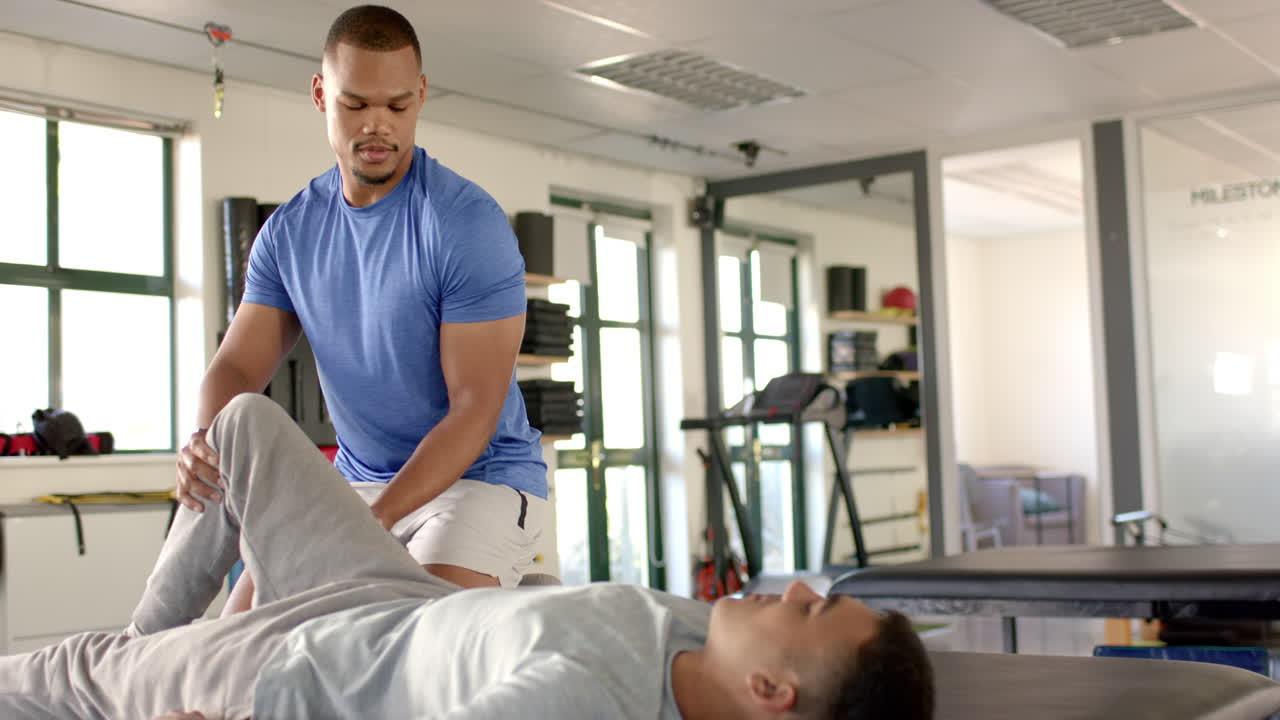 Assisting patient with leg exercises, physical therapist during rehabilitation session