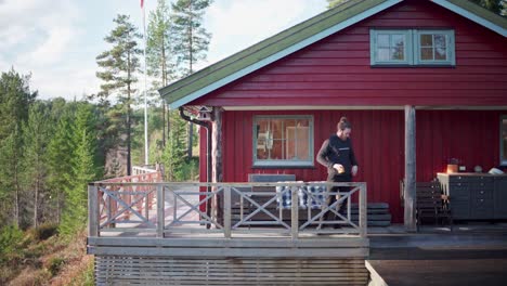 man takes away a cup in the porch of a red cabin