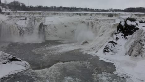 overflowing streams in frosted rugged cliffs during winter at chaudiere falls park in levis, quebec canada - aerial drone shot