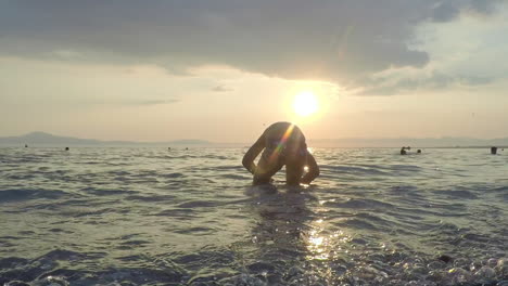 kid plays at the waves with sunset on the background at kalamata beach, greece