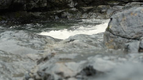 Slow-motion-water-rushing-over-rocks-in-canyon-with-light-rainfall