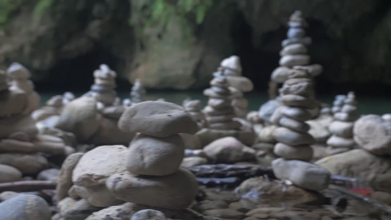 Serene Stone Cairns in a Cave Near Water