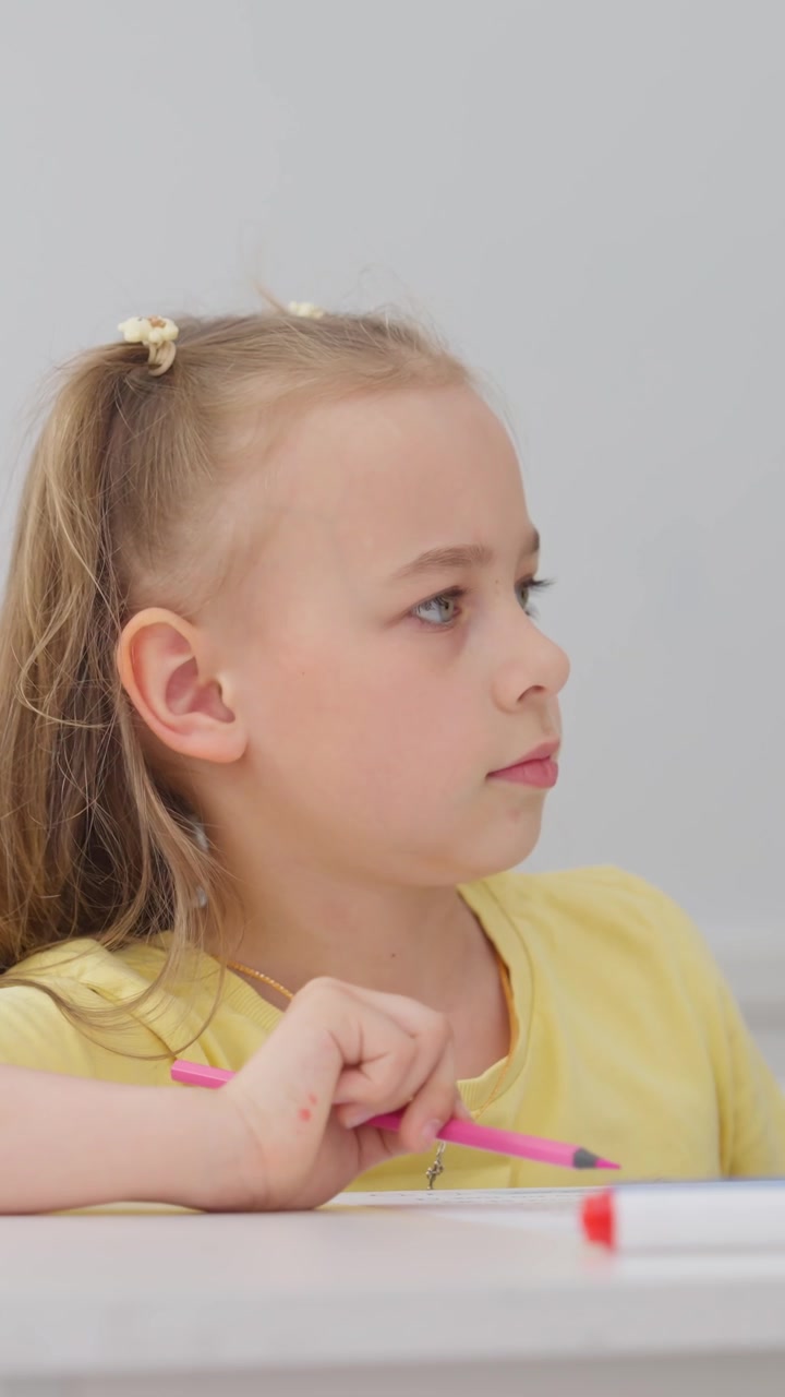 Primo piano di una bambina che disegna con una matita rosa