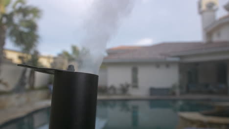 backyard bbq pit smoke stack with smoke coming out in front of pool