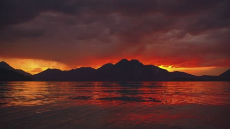 scenic time-lapse cinemagraph / seamless video loop of a beautiful and romantic sunset at natural mountain lake walchensee in southern germany / bavaria with moving red clouds and calm waves in real time at the famous tourist vacation loation. no people.