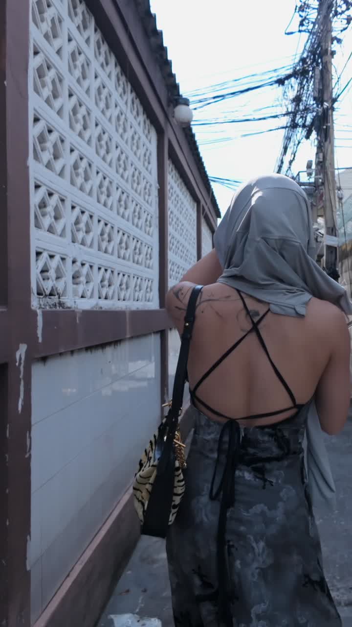 Woman in backless dress and veil walking down an alley