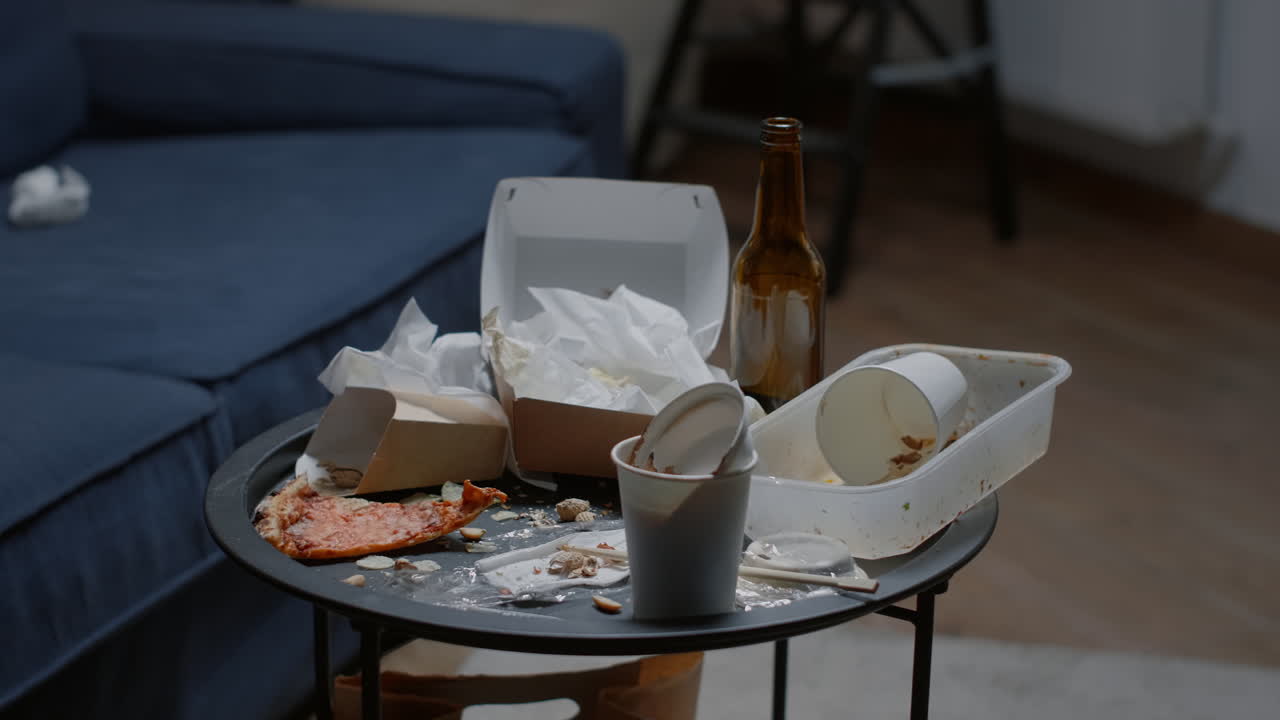 Close up of messy table, leftover food, dirty dishes in empty living room