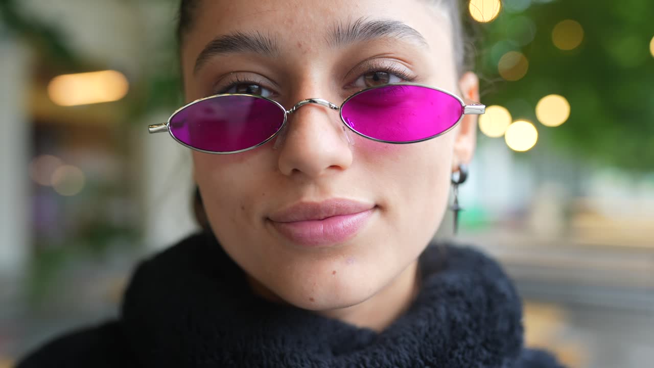 una mujer joven con gafas de sol rosas.