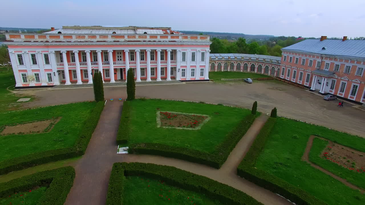 Old palace ensemble with a green flower beds in front. Panorama of little Ukrainian city on the river bank.