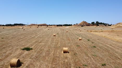 Fardos-De-Paja-Redondos-En-Campos-Secos-De-Tierras-De-Cultivo-De-Chipre,-Rodaje-Aéreo-Hacia-Delante