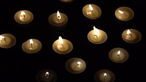 velas en cámara lenta - pequeñas velas ardiendo sobre fondo negro