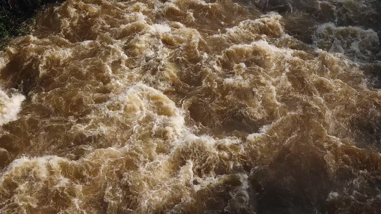 High angle view of muddy flooding river whitewater in slow motion