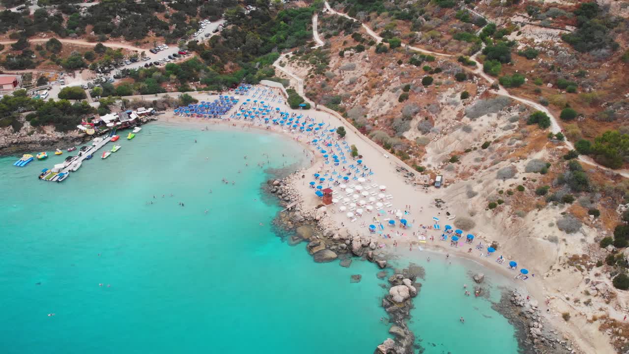 Cinematic drone shot of Konnos Beach at daylight. People swimming and having fun
