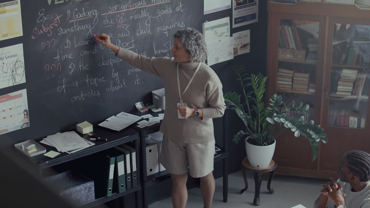 maestra explicando las notas en la pizarra como la conducción de la lección de inglés