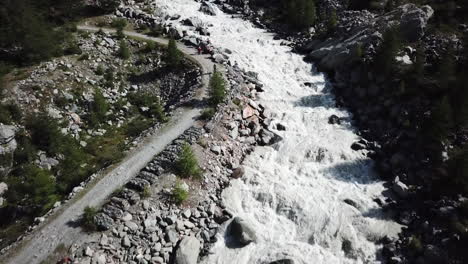 drone aerial view of a muddy turrent inbetween rocks in the swiss alps mountains