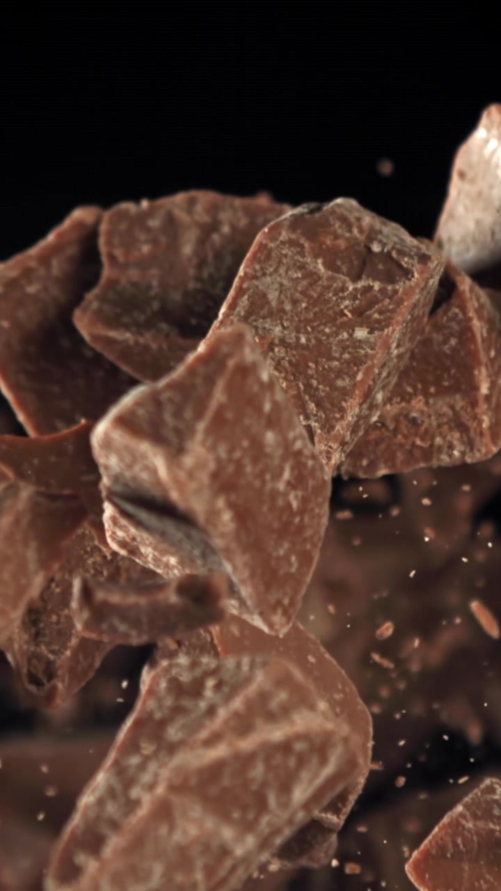 Pezzi di cioccolato che cadono al rallentatore su sfondo nero