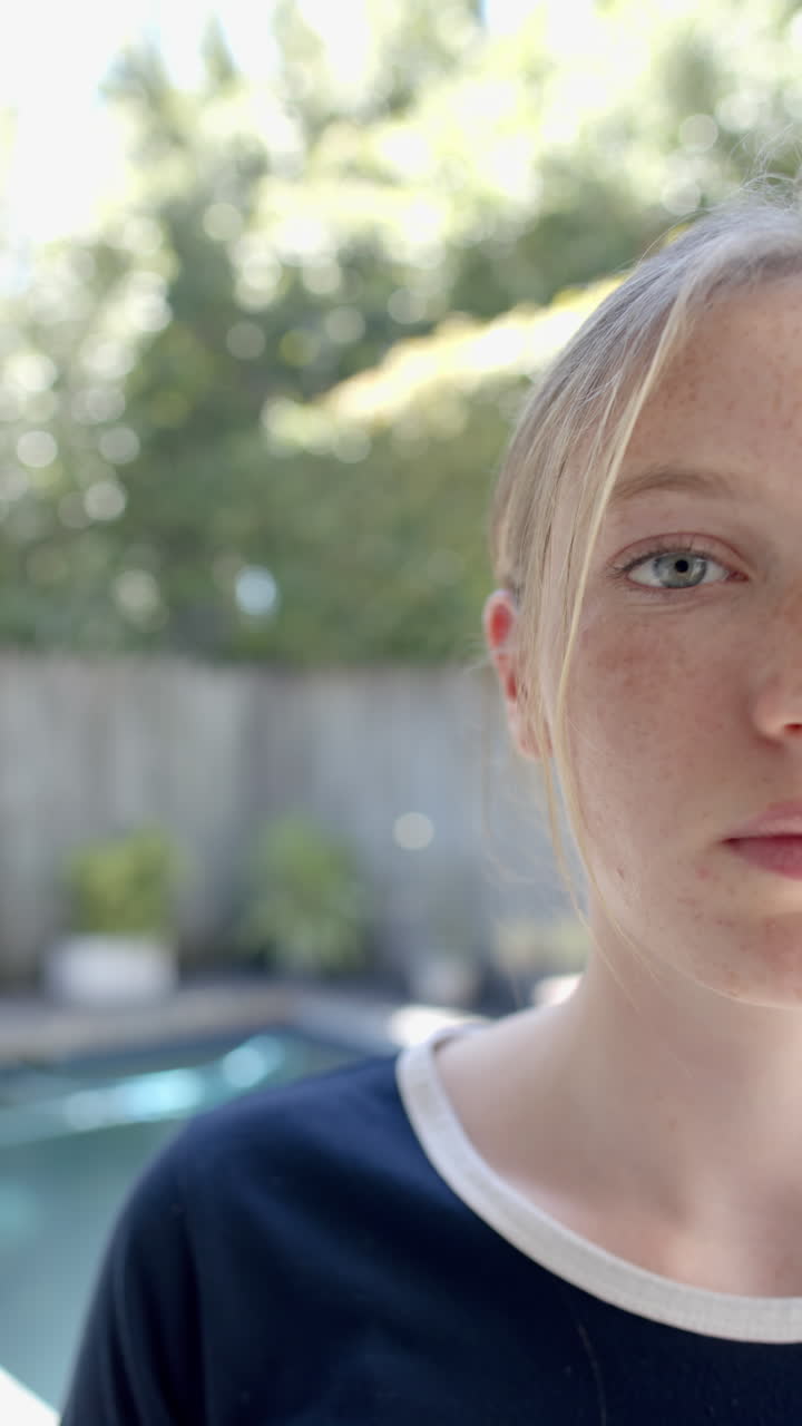 Vertical video of portrait of happy caucasian woman with blond hair in garden, slow motion