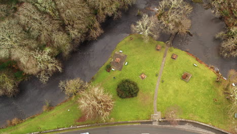 a meandering river surrounded by dense forest and grassy clearings, creating a peaceful nature park alongside road