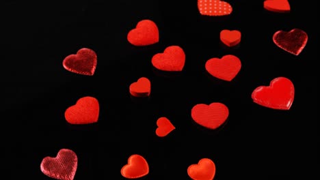 Red-hearts-shapes-falling-on-the-black-surface-4k