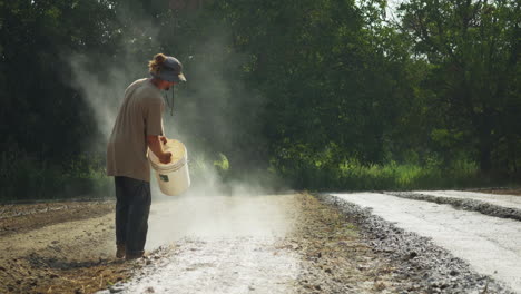 farmer spreading white organic fertilizer un the furrows of a farming fiel, barefoot rural worker