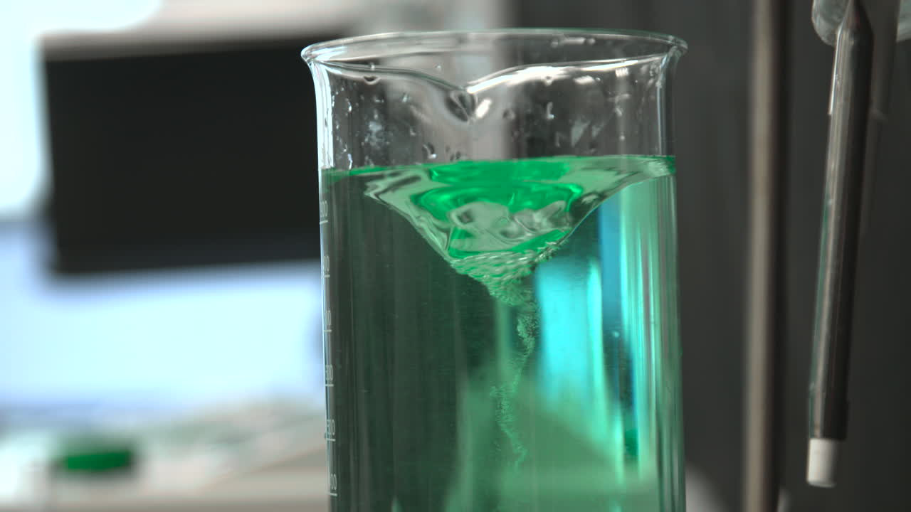 Green Liquid Stirring in a Beaker, Creating a Vortex in a Lab