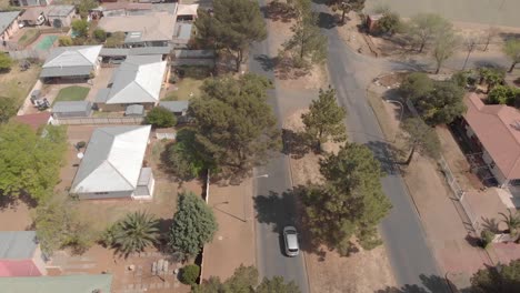 Toma-Aérea-De-Un-Auto-Conduciendo-En-Un-Suburbio-Residencial